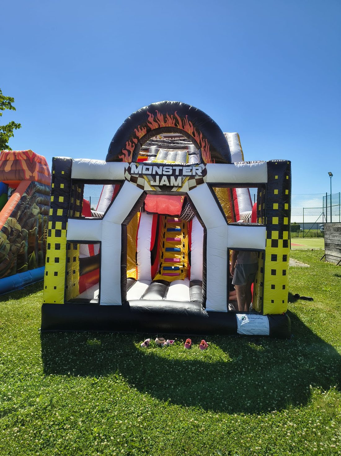 Skákací hrad Monster Jam — vstupní brána z pneumatiky s plameny, uvnitř prolézací dráha a skluzavka
